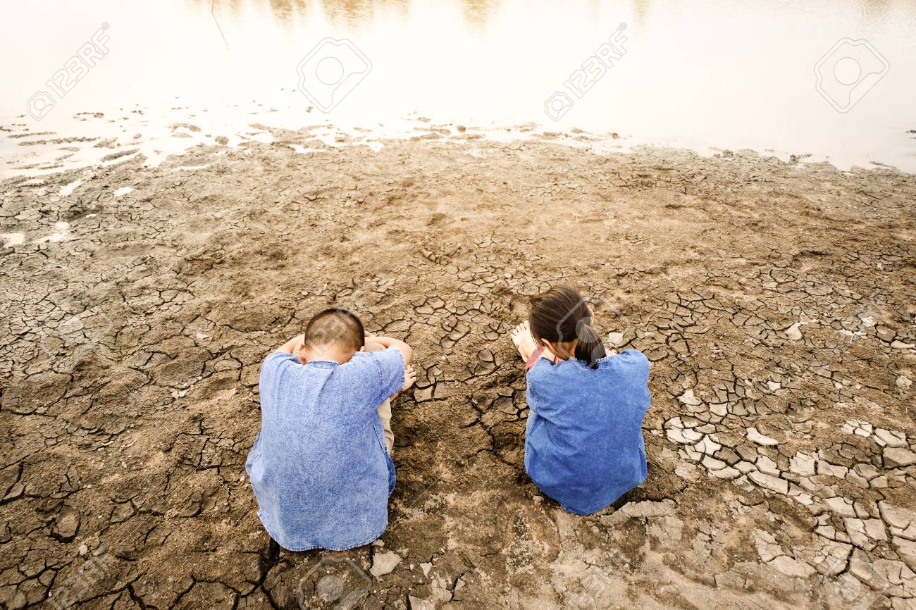Sad Kid Despair Sitting On Cracked Earth On The Arid Lagoon, Natural Disaster. Affected Of Global Warming Made Climate Change. Water Shortage And Drought Concept. Stock Photo, Picture And Royalty Free Image.
