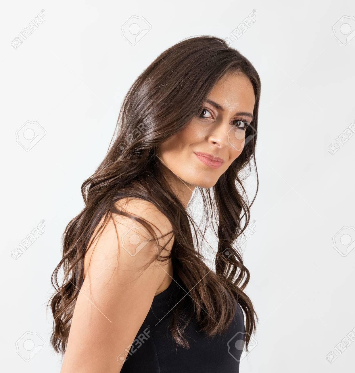 カメラ目線の長いウェーブのかかった髪とゴージャスなフェミニンな女性 灰色のスタジオの背景上の肖像画 の写真素材 画像素材 Image 4171