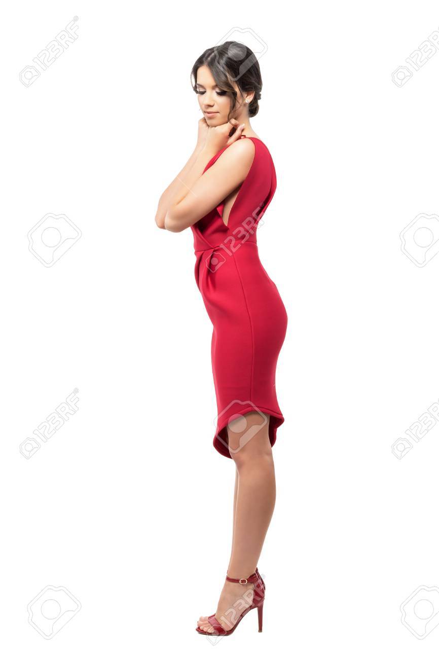 赤いドレスとハイヒールを見下ろしてのあごに両手でフェミニンな女性のプロフィール フルボディの長さの肖像画は 白い背景で隔離 の写真素材 画像素材 Image