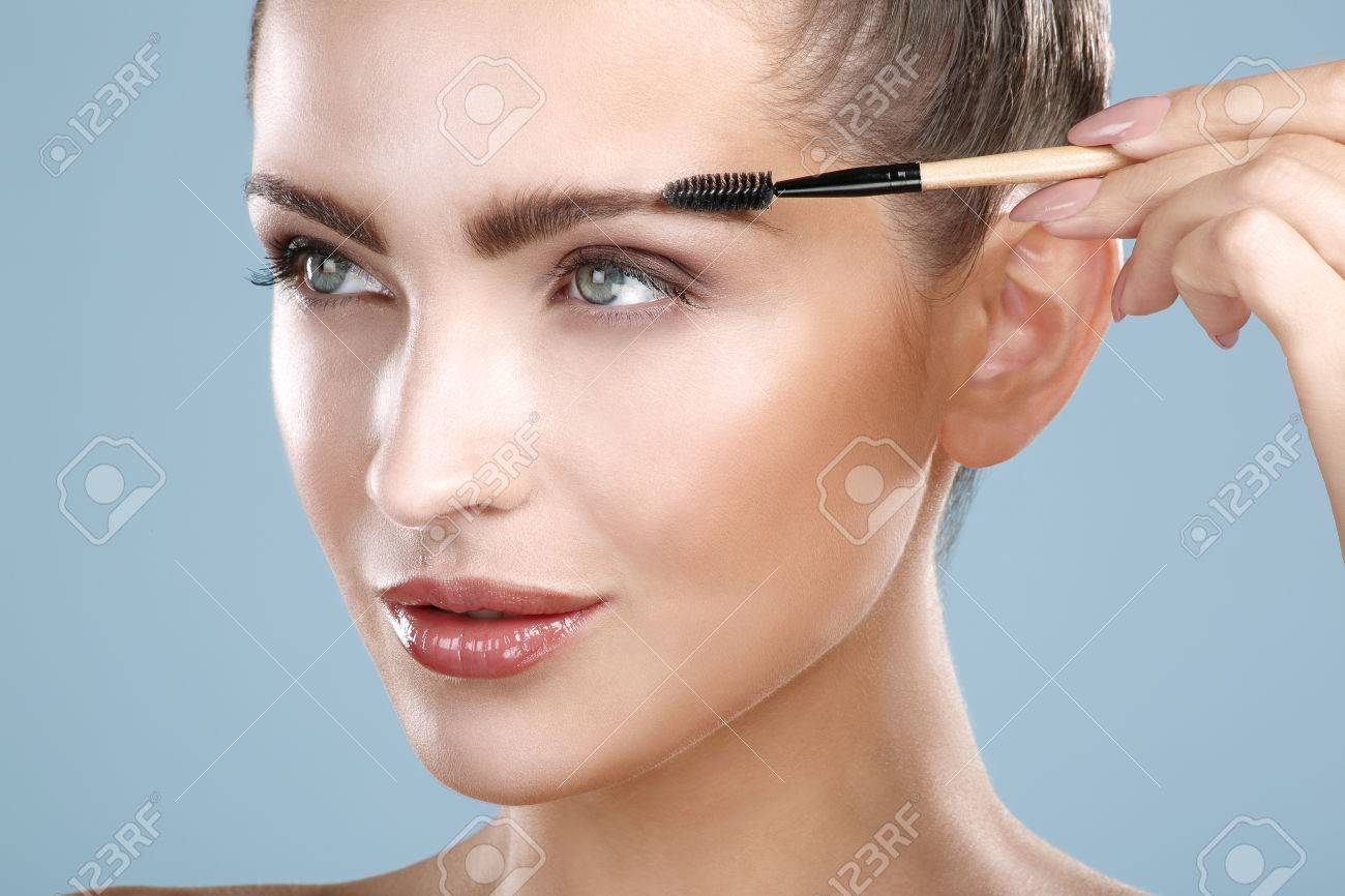 Closeup beautiful woman with eyebrow brush tool on blue - 26159411 Closeup beautiful woman with eyebrow brush tool on blue - 26159411