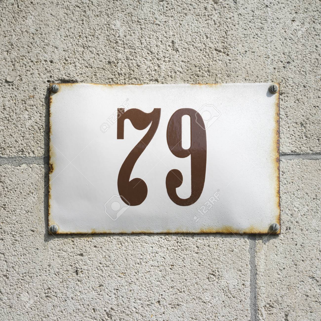 enameled house number on a wall of natural stone stock photo
