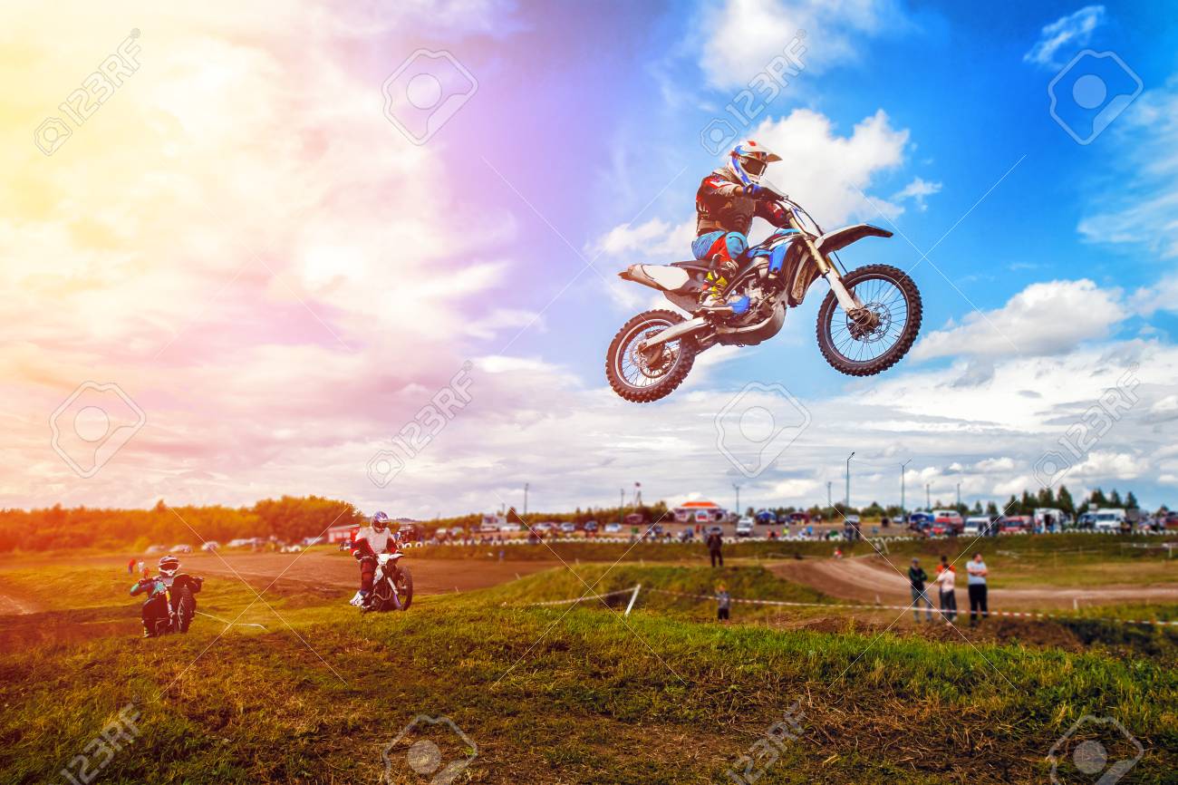 Racer on motorcycle participates in motocross cross-country in flight, jumps and takes off on springboard against sky. Concept active extreme rest. - 95190220 Racer on motorcycle participates in motocross cross-country in flight, jumps and takes off on springboard against sky. Concept active extreme rest. - 95190220