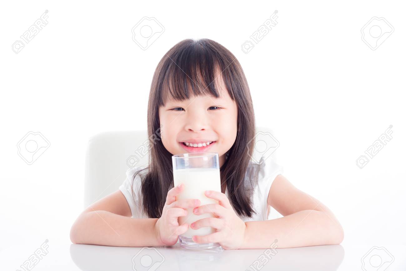 Little asian girl sitting and holding a glass of milk over white background - 87705093 Little asian girl sitting and holding a glass of milk over white background - 87705093