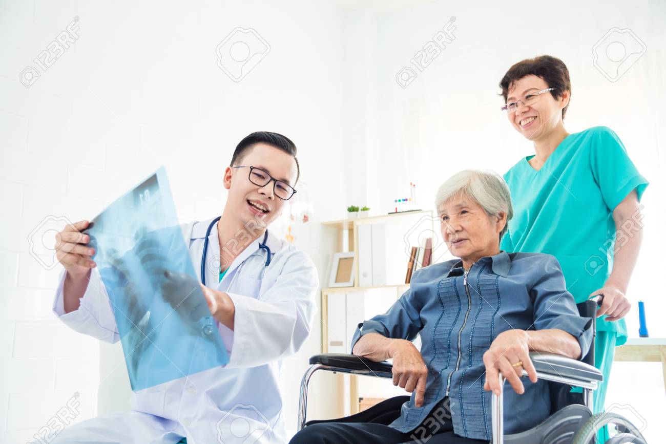 Asian doctor explain X-ray flim result to his patient in hospital - 100069540 Asian doctor explain X-ray flim result to his patient in hospital - 100069540