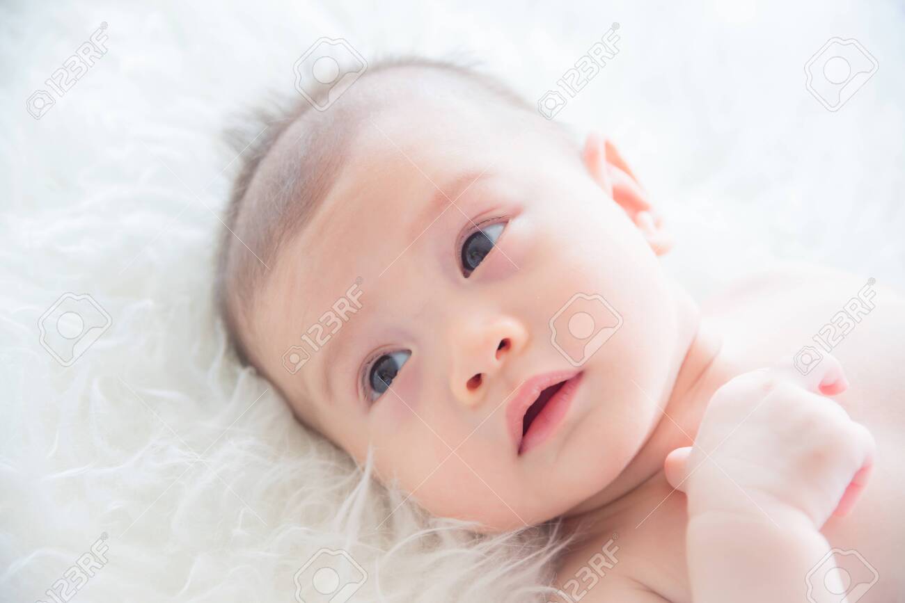 Little asian baby lying on bed - 123954753 Little asian baby lying on bed - 123954753