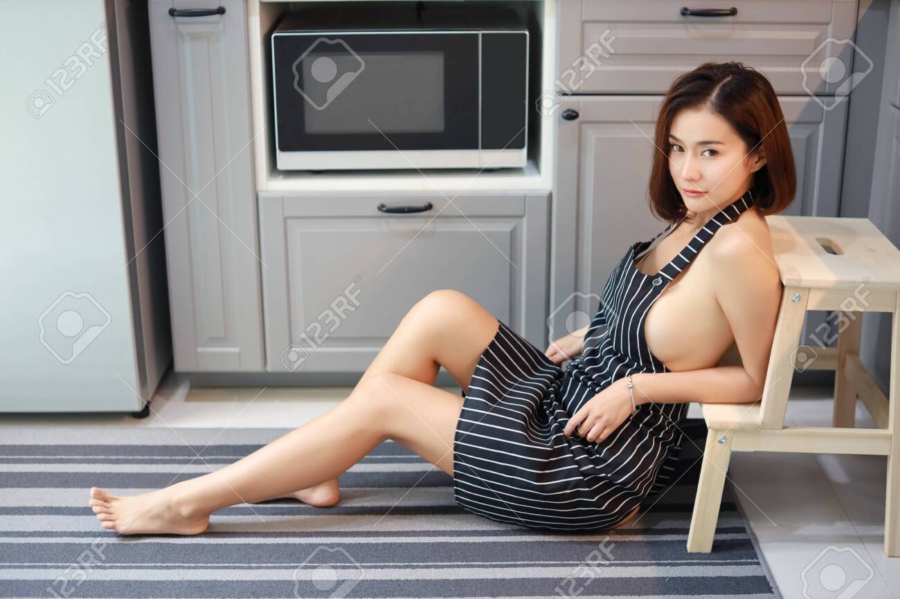 Toma Completa De Una Mujer Asiática Y Atractiva, Esposa De Pelo Corto Con Delantal Blanco Y Negro, Sin Sostén, Ella Sentada Descansa Mientras Cocina En La Cocina Y Mira La Cámara (concepto esposa 1300x866 foto de alta calidad Toma Completa De Una Mujer Asiática Y Atractiva, Esposa De Pelo Corto Con Delantal Blanco Y Negro, Sin Sostén, Ella Sentada Descansa Mientras Cocina En La Cocina Y Mira La Cámara (concepto Foto