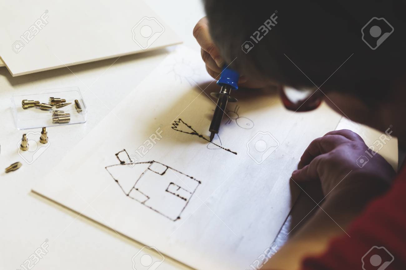 mentally disabled woman is doing woodburning as art therapy, horizontal - 63947648 mentally disabled woman is doing woodburning as art therapy, horizontal - 63947648