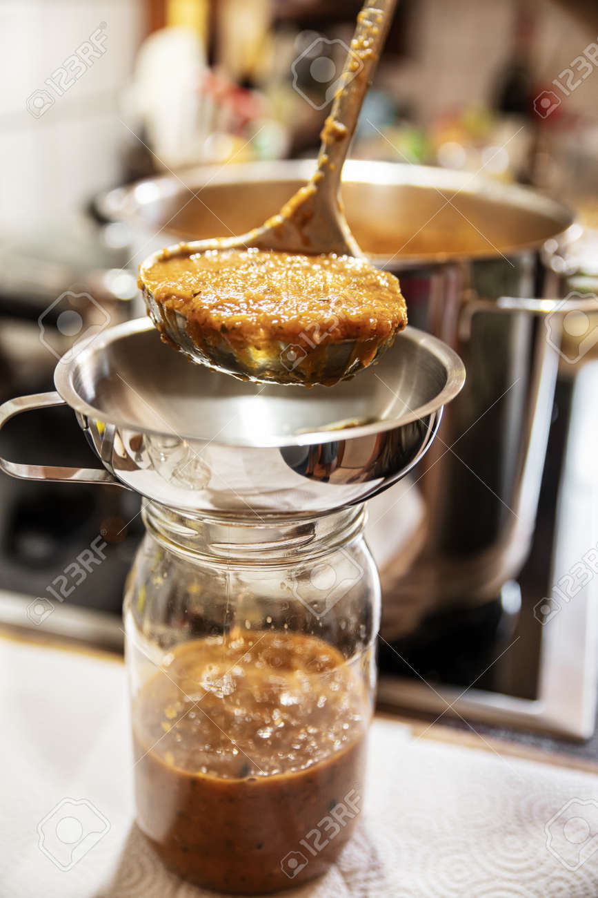 fresh cooked vegetable sauce will be filled through an funnel into a glass, concept preserving food for winter - 168974727 fresh cooked vegetable sauce will be filled through an funnel into a glass, concept preserving food for winter - 168974727