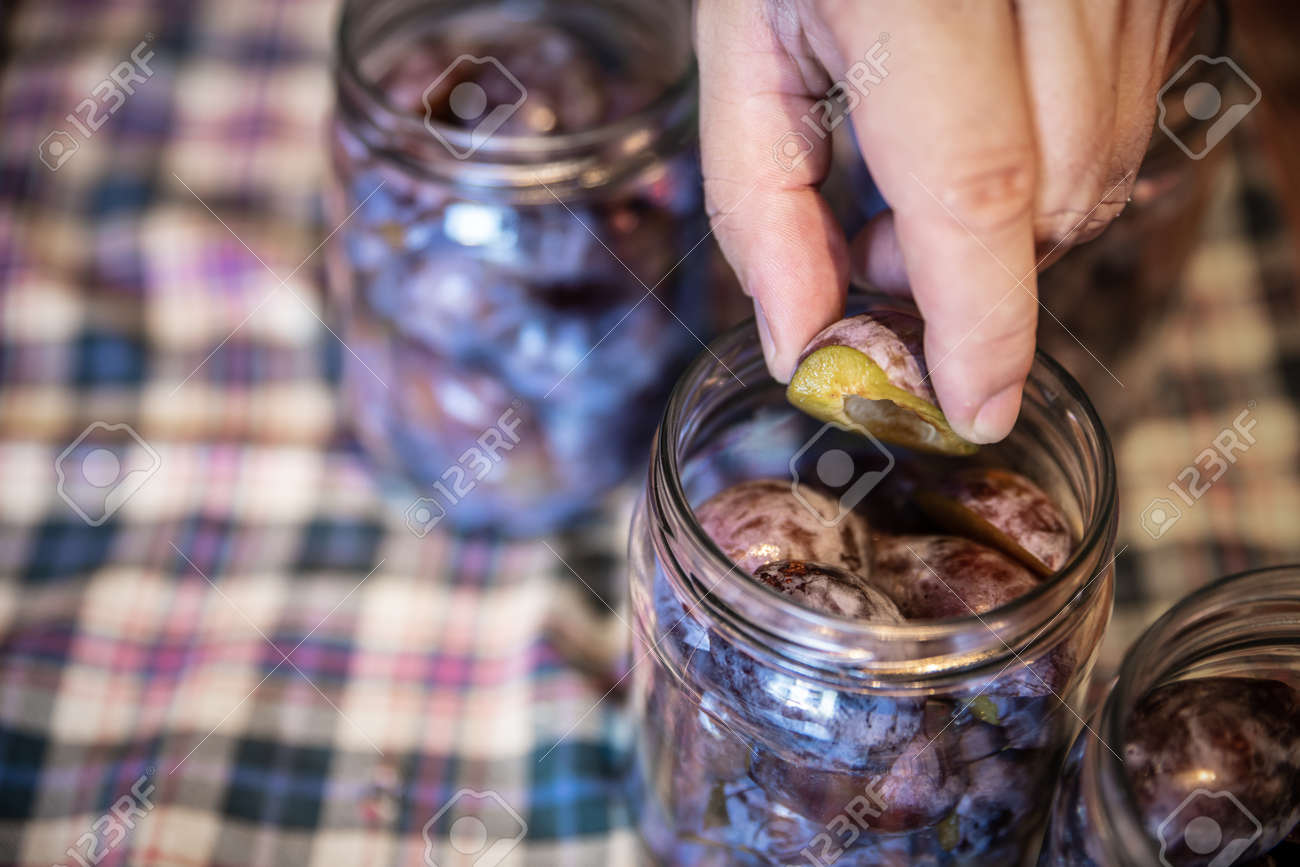 a man is filling glasses with plums, preparing for preserving the fruits, concept self supporter or gardening - 168974756 a man is filling glasses with plums, preparing for preserving the fruits, concept self supporter or gardening - 168974756