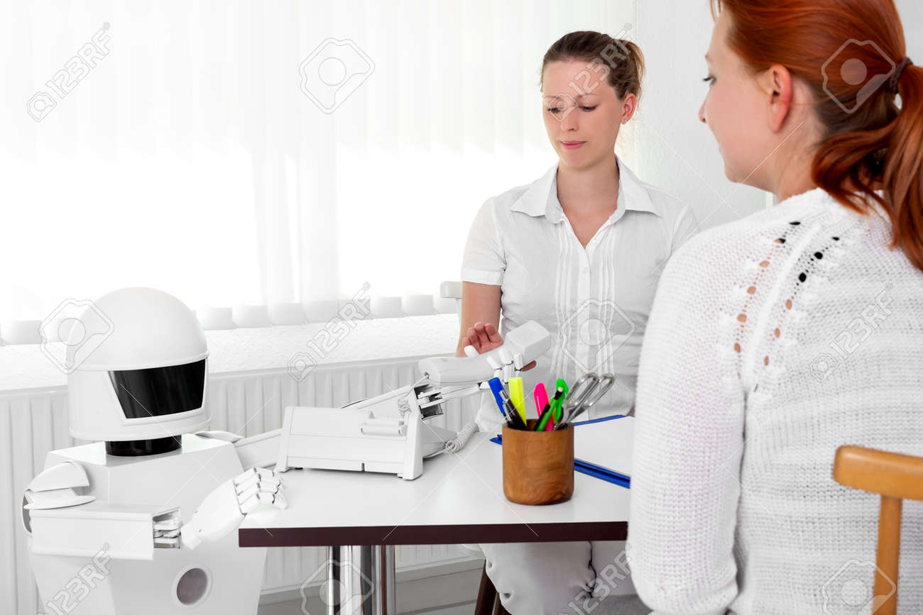 autonomous medical robot is giving a telephone to a female doctor in her office, while sitting behind her desktop - 170381911 autonomous medical robot is giving a telephone to a female doctor in her office, while sitting behind her desktop - 170381911