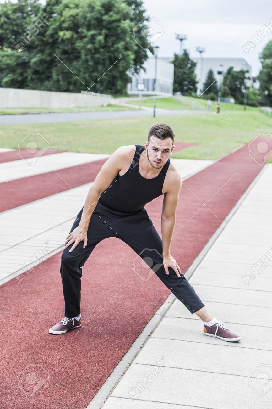 Atleta Joven En Ropa Deportiva Negro Preparándose Para Entrenamiento O Una Competencia En Pista Roja Corriendo En Verano Fotos, Retratos, Imágenes Y De Archivo De Derecho. Image 84610018.