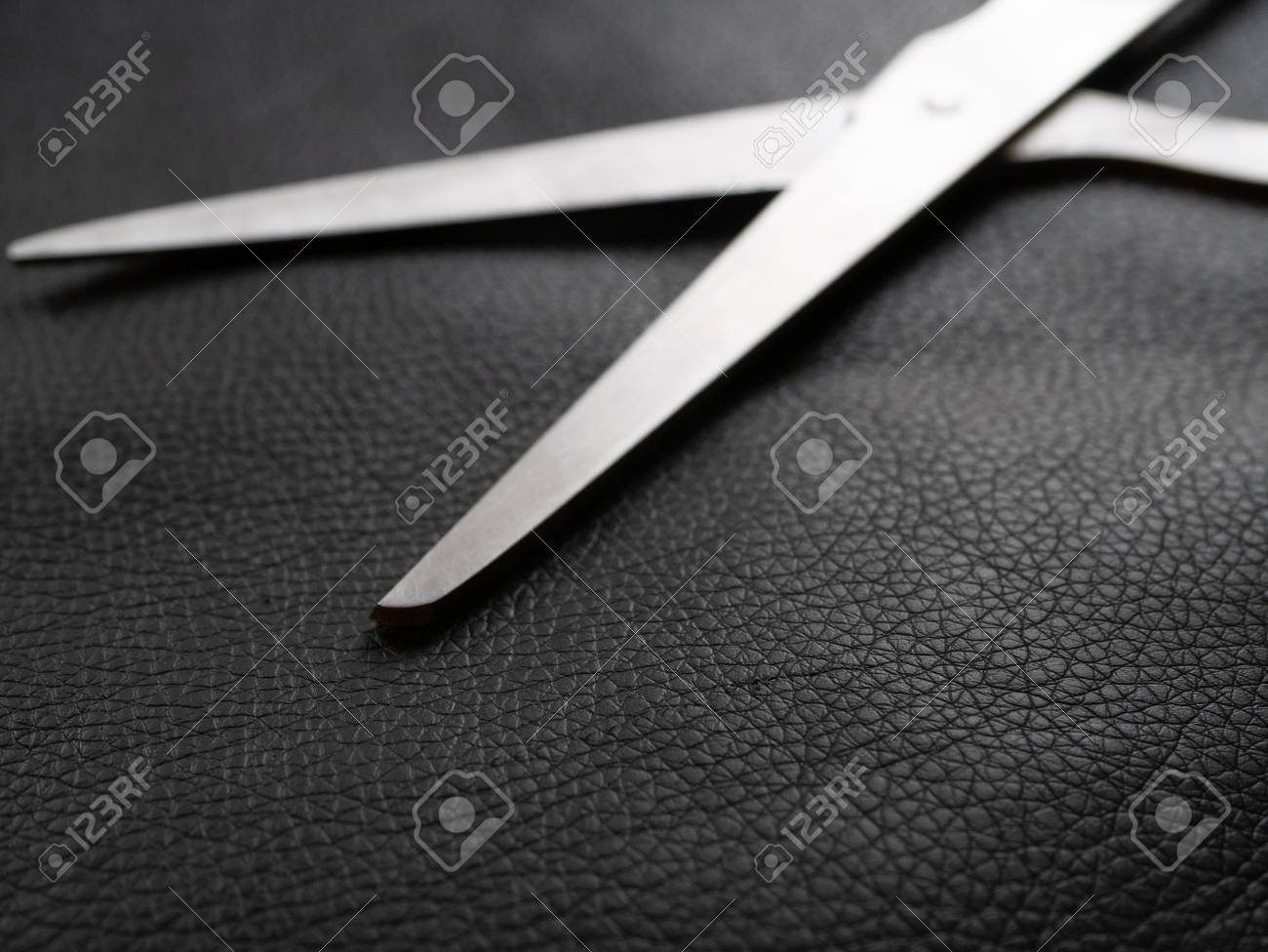 shiny metal scissors on a piece of natural black leather. craft work small business concept. selective focus on leather - 108738907 shiny metal scissors on a piece of natural black leather. craft work small business concept. selective focus on leather - 108738907