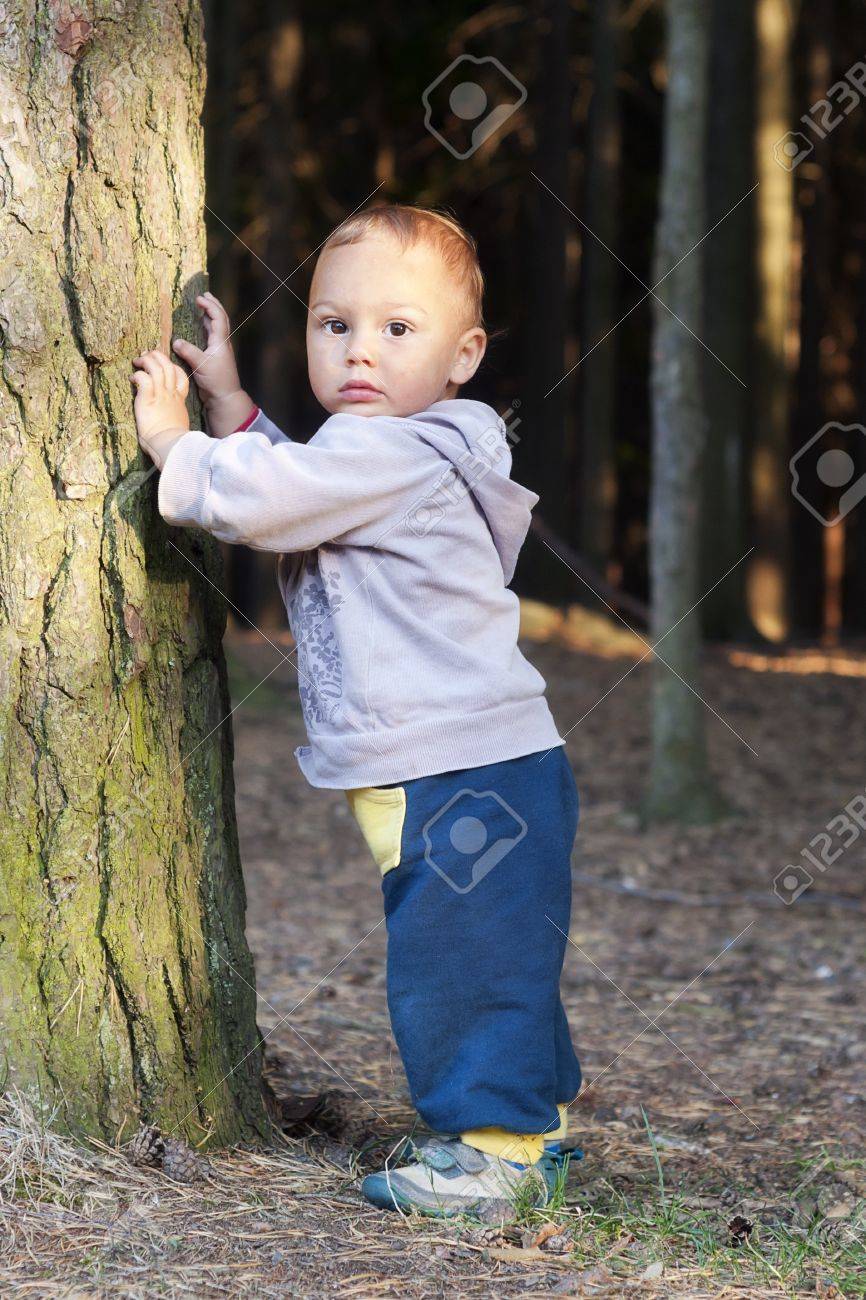 森の木のそばに立って、性格かわいい幼児。 ロイヤリティーフリーフォト