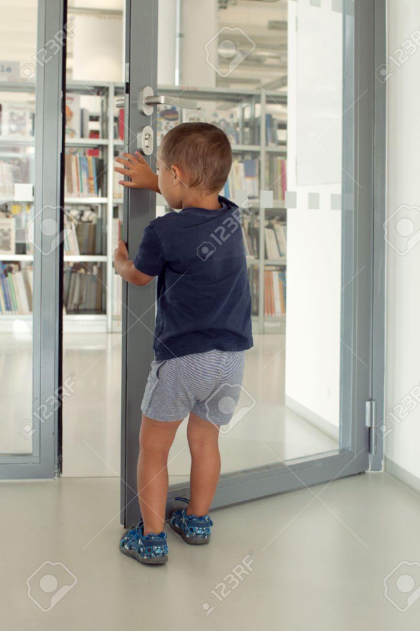 子供はドアを開けるとパブリックまたは学校の図書室に入る の写真素材 画像素材 Image