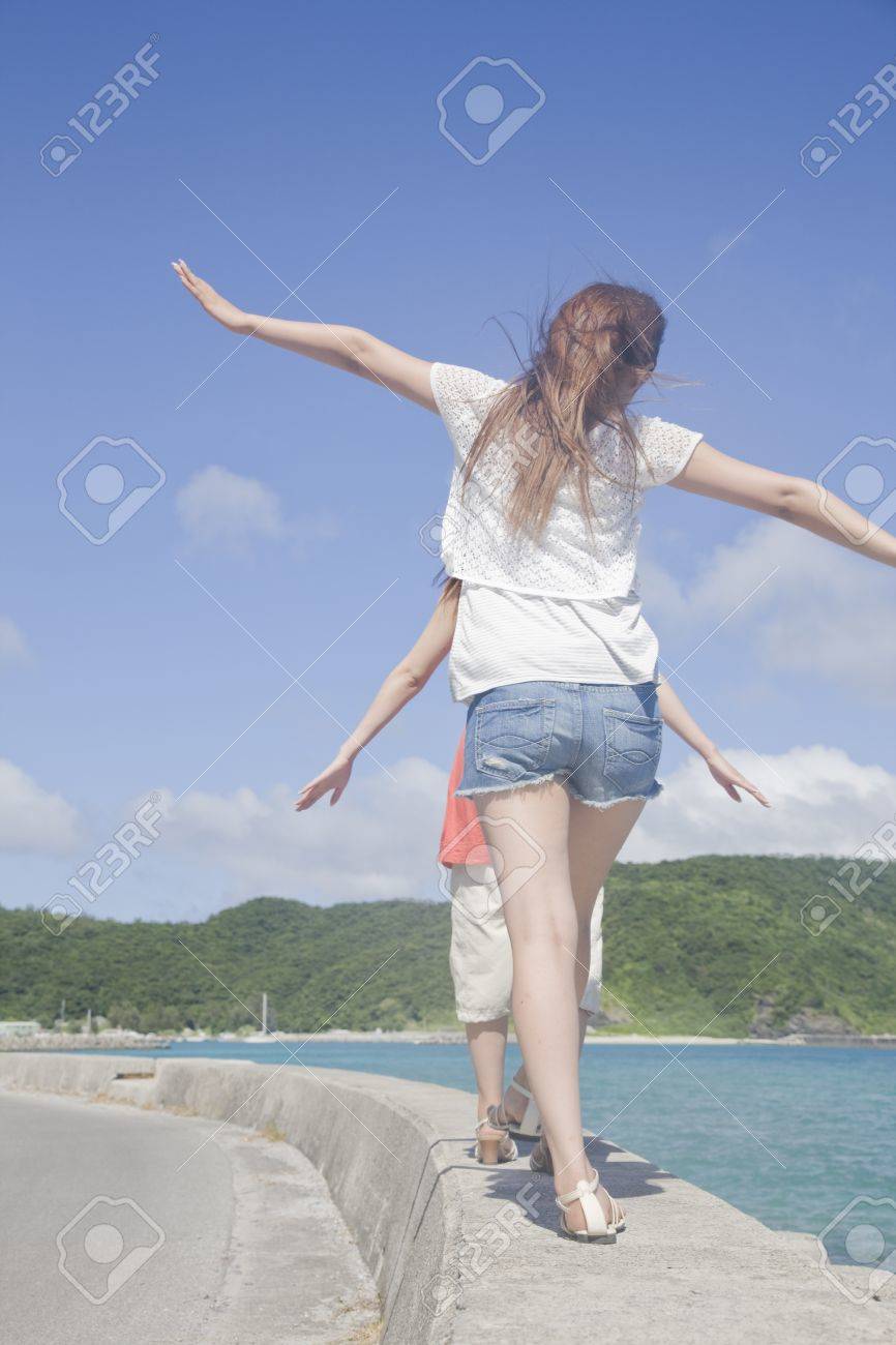 海辺の防波堤を歩いている二人の女性の後ろから の写真素材 画像素材 Image