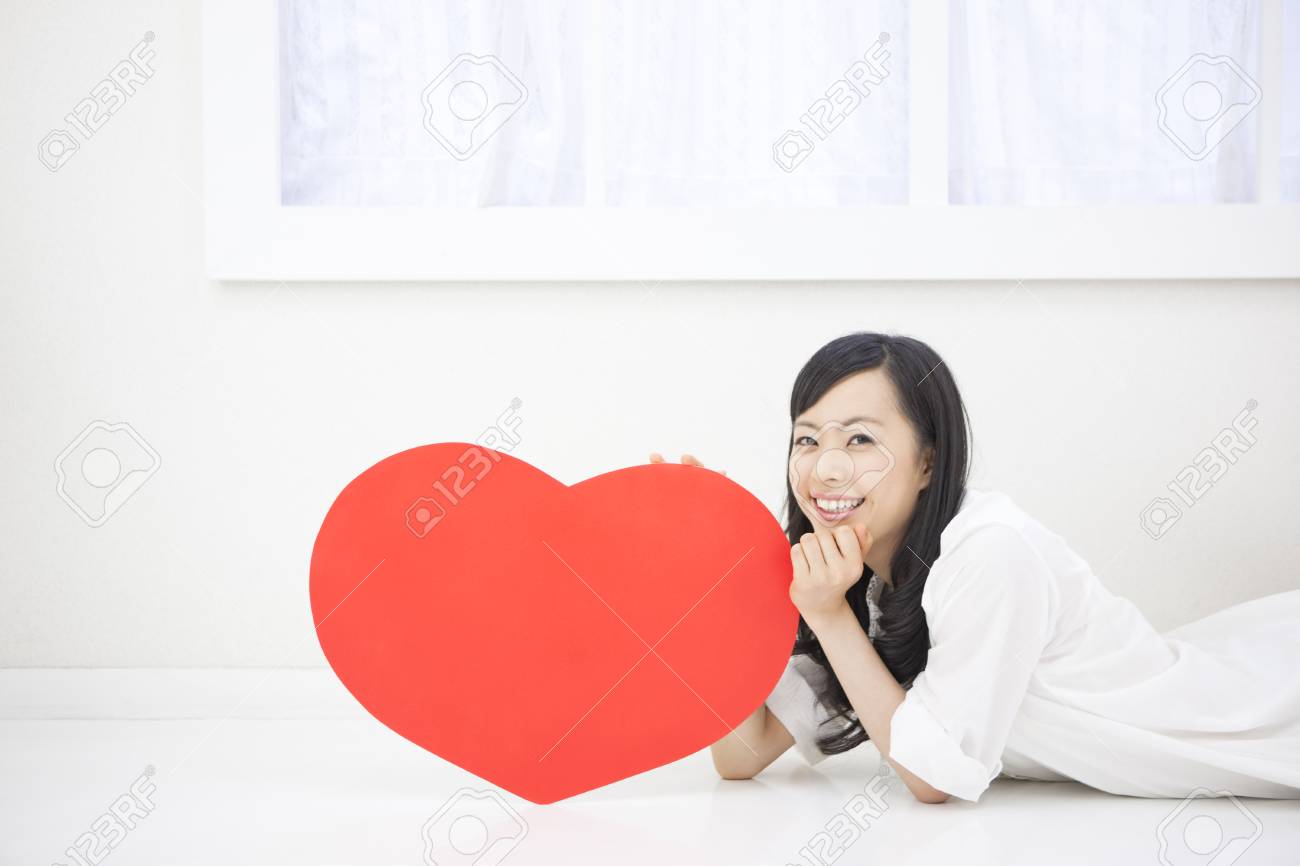横になっているハート型のボードを持つ女性 の写真素材 画像素材 Image