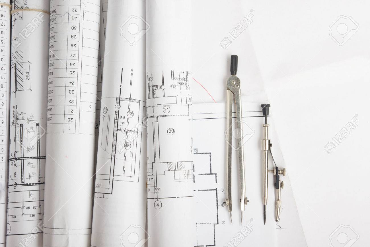 Workplace of architect - Architectural project, blueprints, rolls and tablet, pen, divider compass on plans. Engineering tools view from the top. Construction background. Copy space for text - 50996801 Workplace of architect - Architectural project, blueprints, rolls and tablet, pen, divider compass on plans. Engineering tools view from the top. Construction background. Copy space for text - 50996801