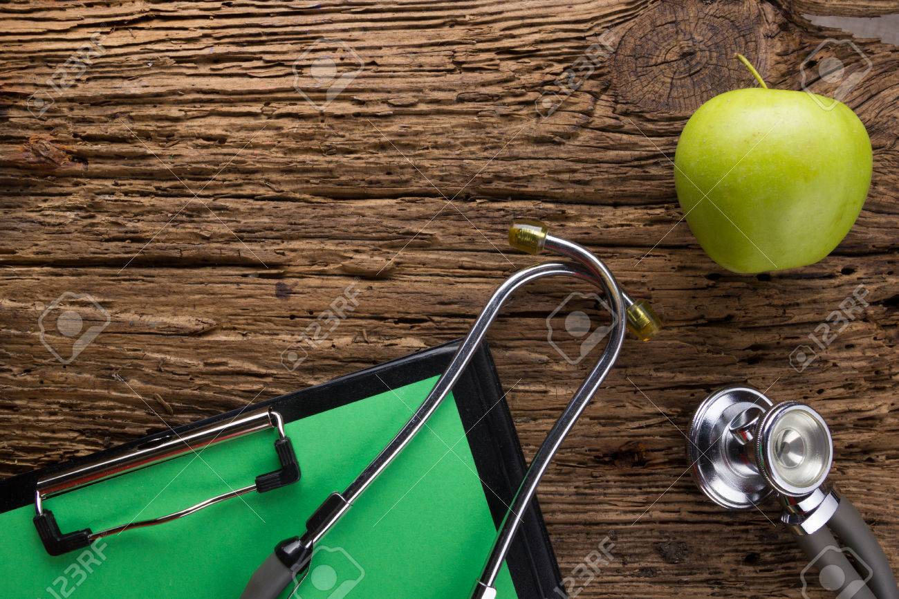 Alternative medicine - stethoscope, clipboard and green apple on wood table top view . Medical background. Concept for diet, healthcare, nutrition or medical insurance. - 50997199 Alternative medicine - stethoscope, clipboard and green apple on wood table top view . Medical background. Concept for diet, healthcare, nutrition or medical insurance. - 50997199