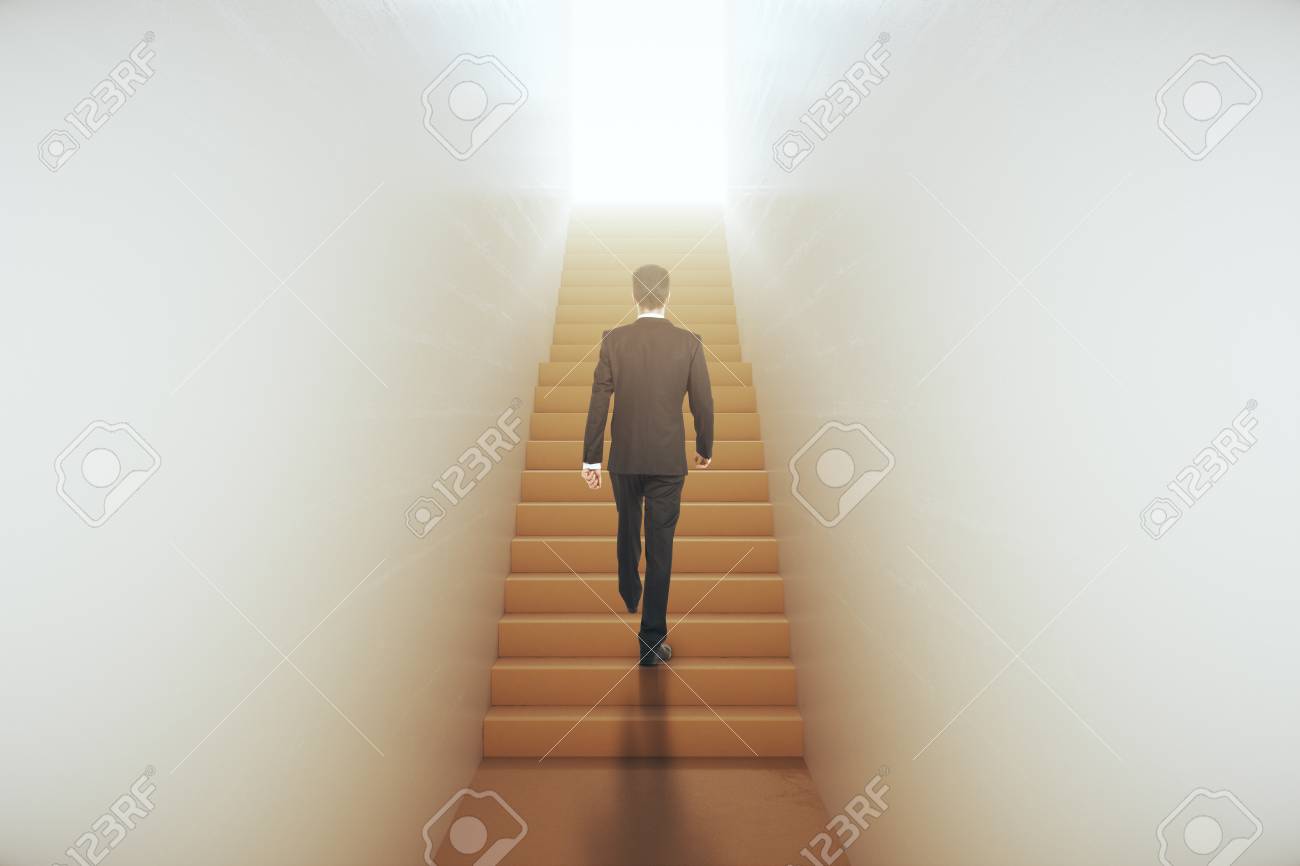 明るい光につながる狭いの抽象のはしごを登るスーツの青年実業家の背面します 成功のコンセプトです 3 D レンダリング の写真素材 画像素材 Image