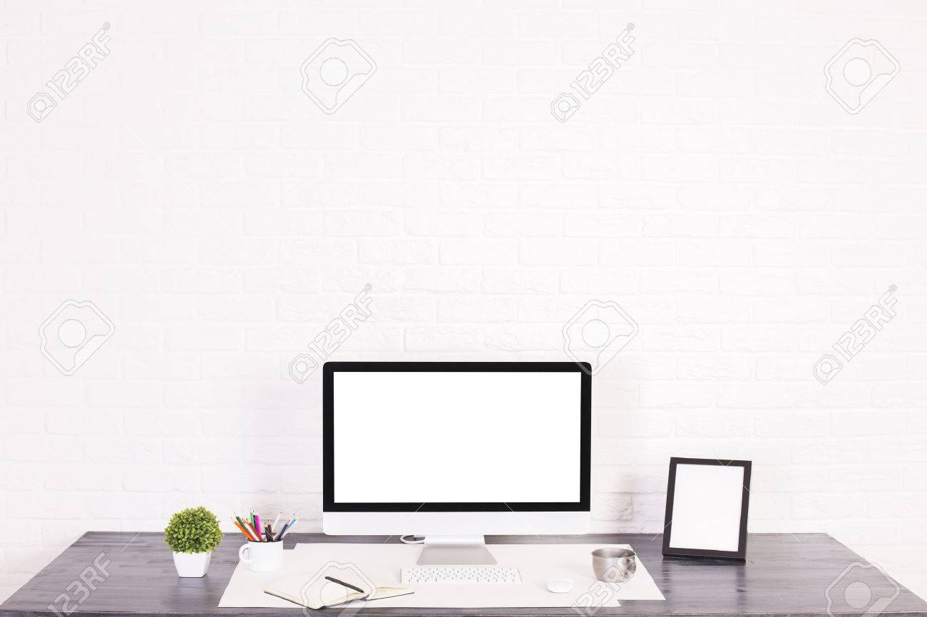 designer desktop with blank white computer monitor picture frame