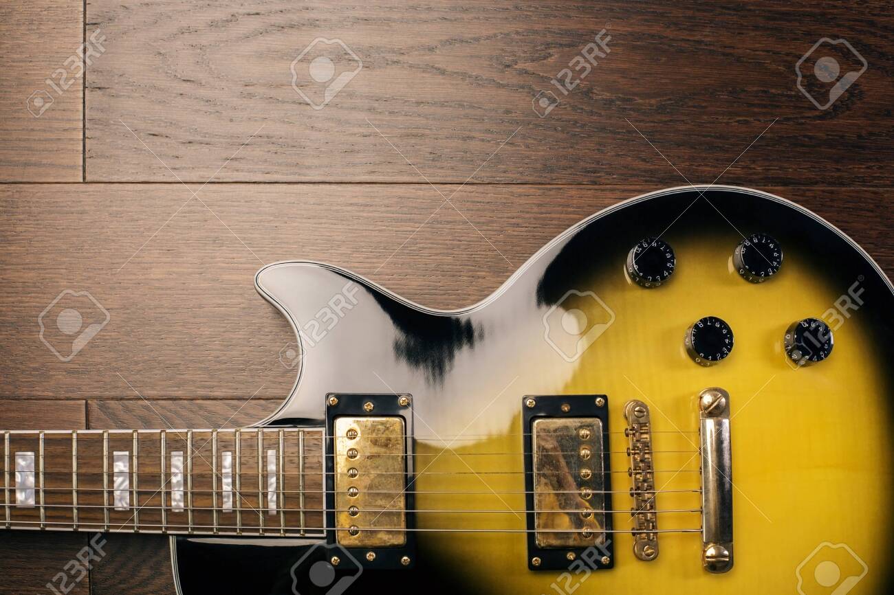 Black And Yellow Electric Guitar On Wooden Brown Surface Closeup