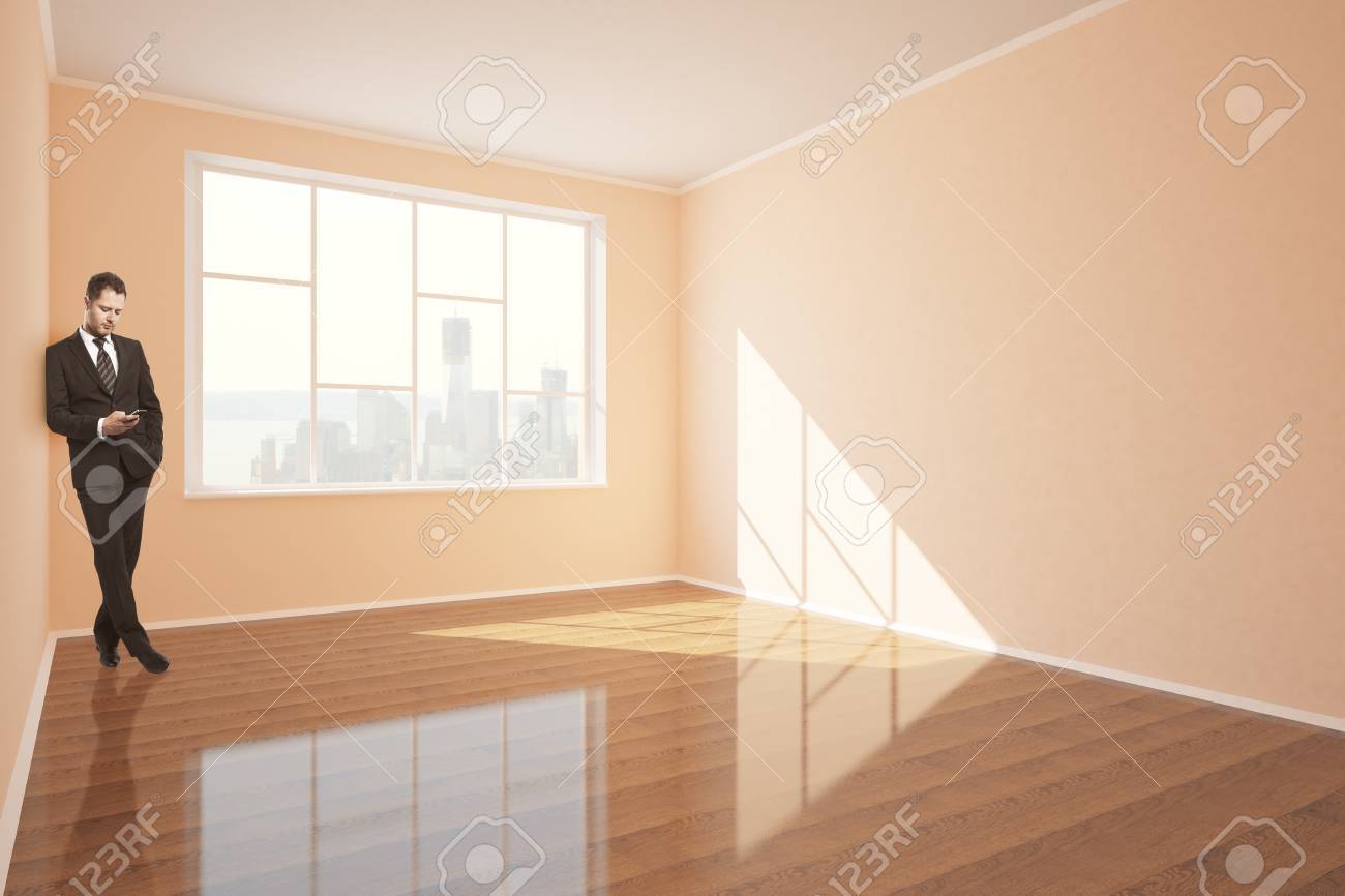 Businessman Using Smartphone In Interior With Shiny Wooden Floor