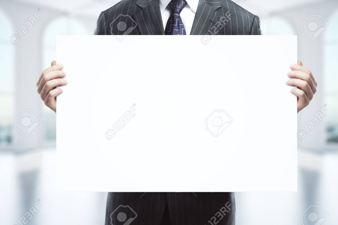Download Businessman In Suit Holding Empty Whiteboard On Blurry Interior Stock Photo Picture And Royalty Free Image Image 64000993