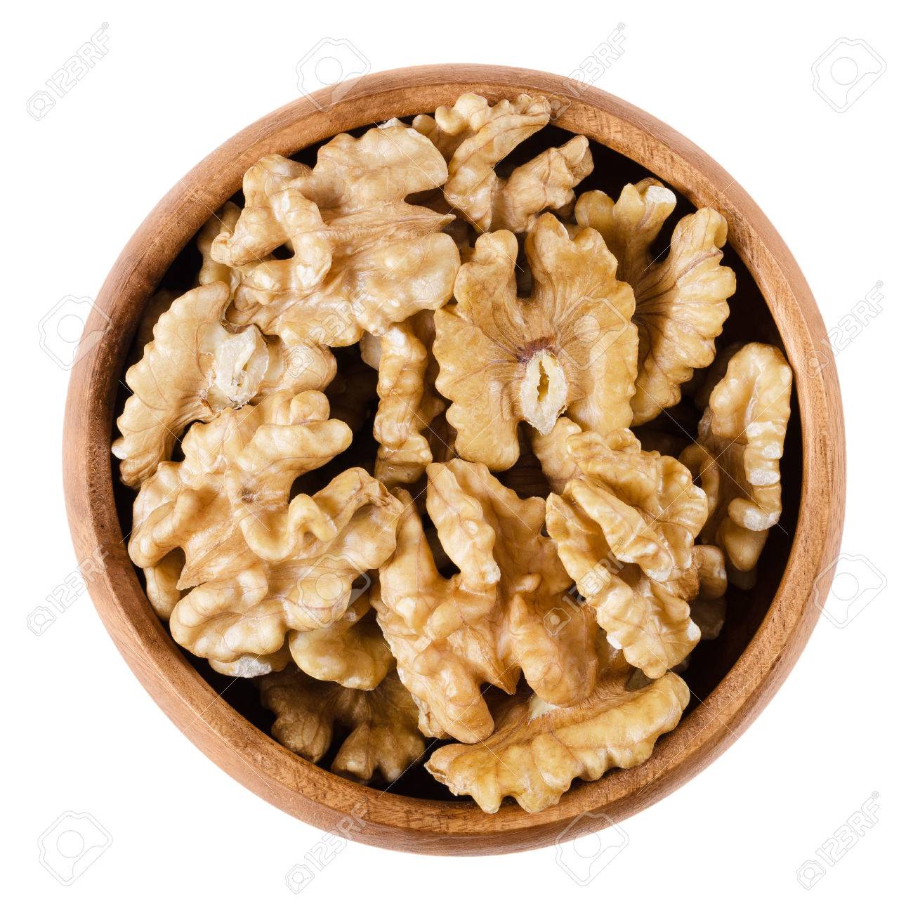 Walnut kernel halfs in a wooden bowl on white background. Brown dried seeds of common walnuts, Juglans regia. Edible, organic and vegan food. Isolated macro photo close up from above. - 62146016 Walnut kernel halfs in a wooden bowl on white background. Brown dried seeds of common walnuts, Juglans regia. Edible, organic and vegan food. Isolated macro photo close up from above. - 62146016