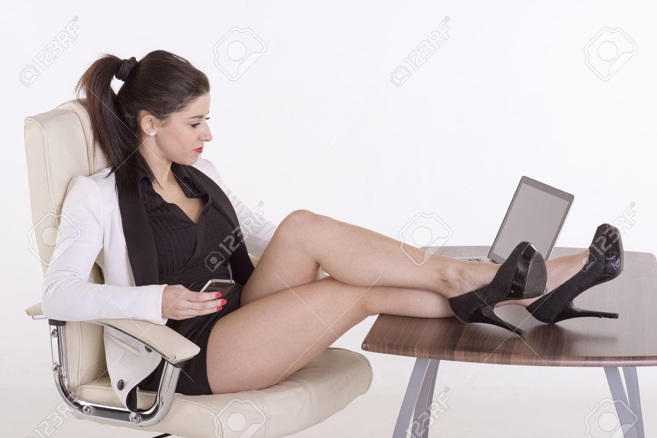 携帯電話を使用して机の上の足を持つ秘書 の写真素材 画像素材 Image