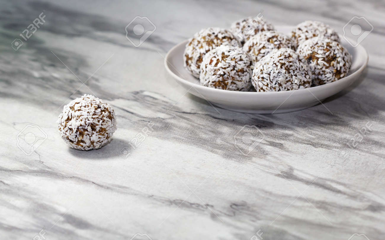 Homemade energy balls with dried apricots, raisins, dates, prunes, walnuts and coconut. Healthy sweet food. Energy balls in a plate on a marble gray background. Close up. Side view. Copy space - 170430090 Homemade energy balls with dried apricots, raisins, dates, prunes, walnuts and coconut. Healthy sweet food. Energy balls in a plate on a marble gray background. Close up. Side view. Copy space - 170430090