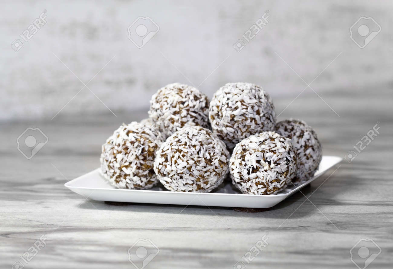 Homemade energy balls with dried apricots, raisins, dates, prunes, walnuts and coconut. Healthy sweet food. Energy balls in a plate on a marble gray background. Close up. Side view. Copy space - 170430146 Homemade energy balls with dried apricots, raisins, dates, prunes, walnuts and coconut. Healthy sweet food. Energy balls in a plate on a marble gray background. Close up. Side view. Copy space - 170430146