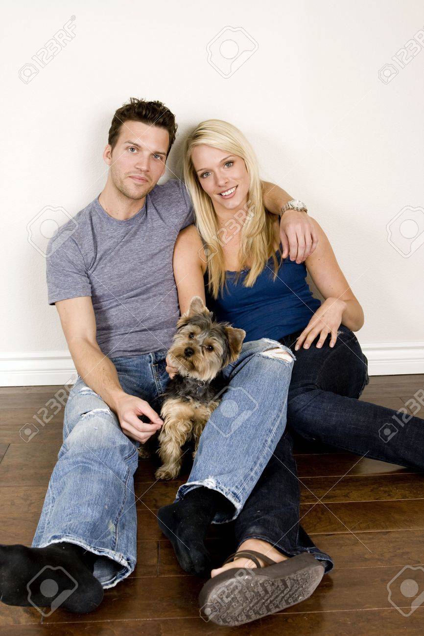 Attractive young couple sitting in their new home with their dog - 5065288 Attractive young couple sitting in their new home with their dog - 5065288