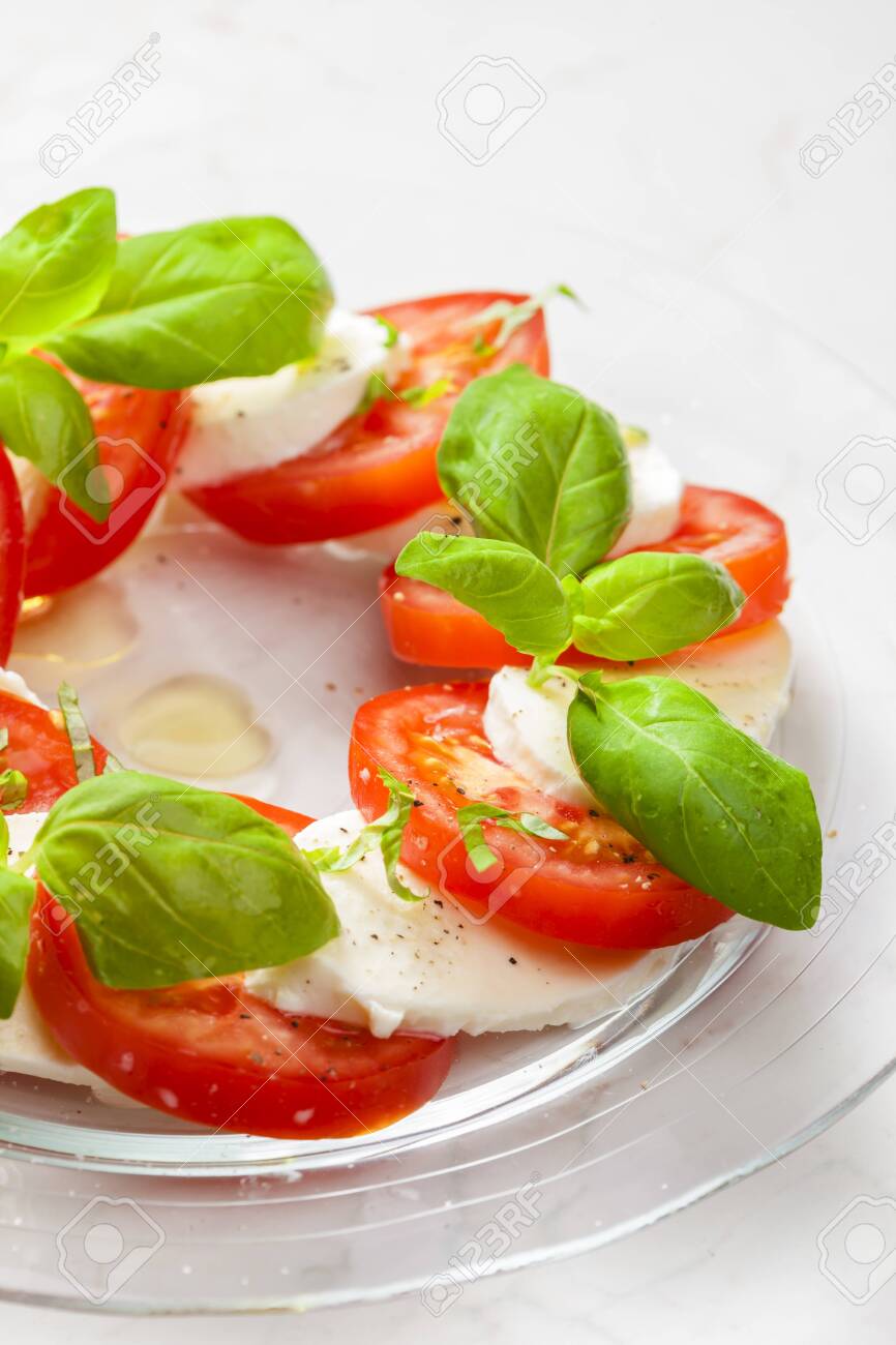 Delicious caprese salad with ripe tomatoes and mozzarella cheese with fresh basil leaves. Italian food - 138041644 Delicious caprese salad with ripe tomatoes and mozzarella cheese with fresh basil leaves. Italian food - 138041644