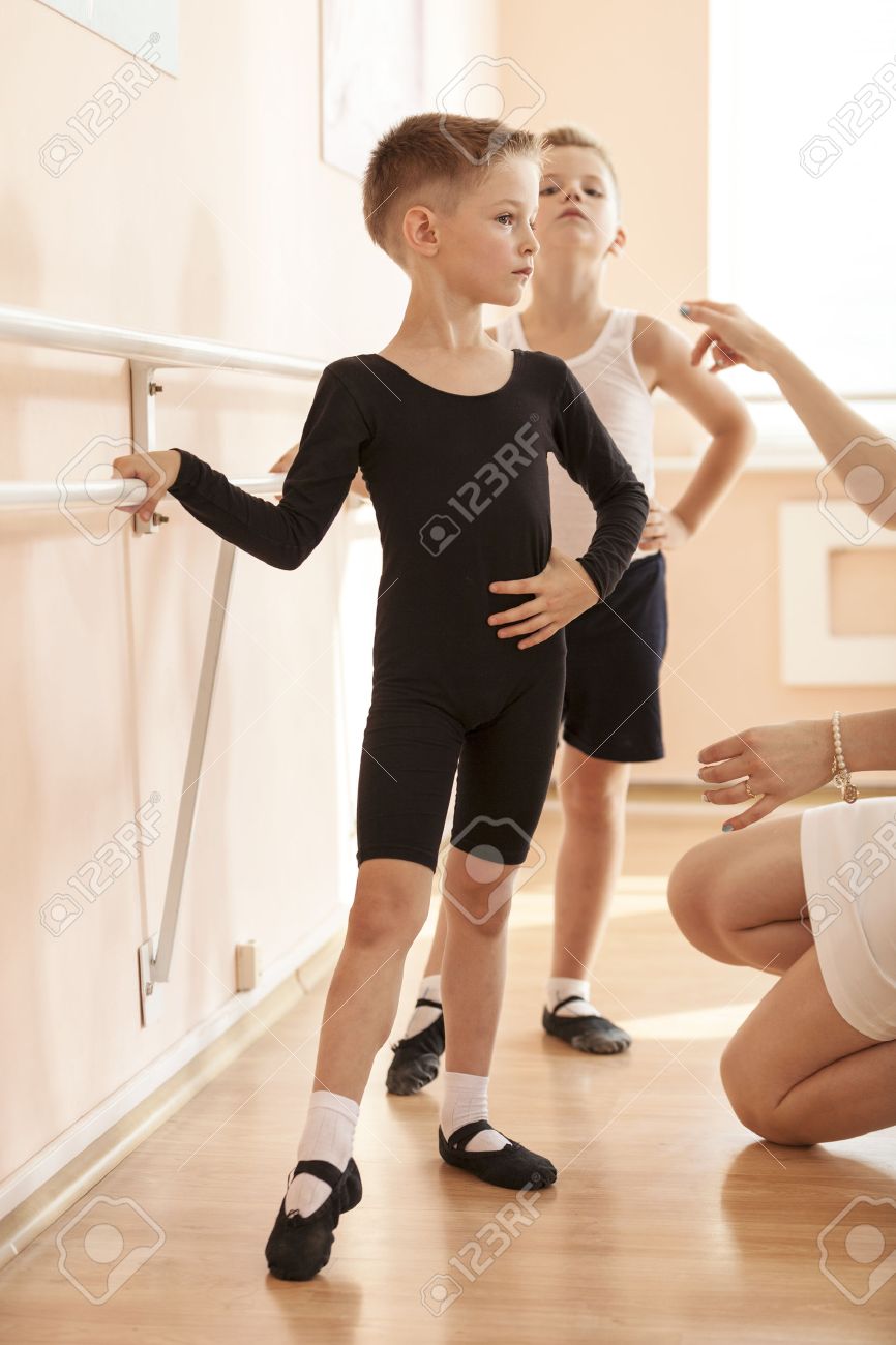 Young boys working at the barre in a ballet dance class. Teacher adjusting the position of one of them. - 48931345 Young boys working at the barre in a ballet dance class. Teacher adjusting the position of one of them. - 48931345