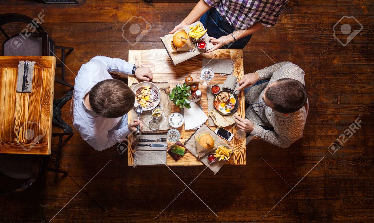 Young men having lunch at a cafe, view from above - 55687727 Young men having lunch at a cafe, view from above - 55687727