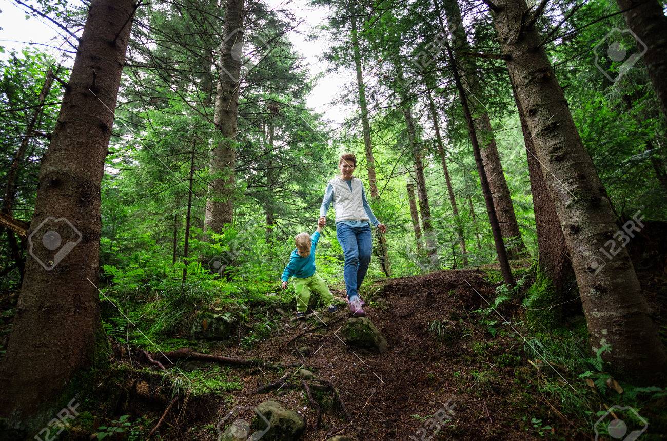 Young woman and toddler son walking down a path in a mountainous forest - 61072392 Young woman and toddler son walking down a path in a mountainous forest - 61072392