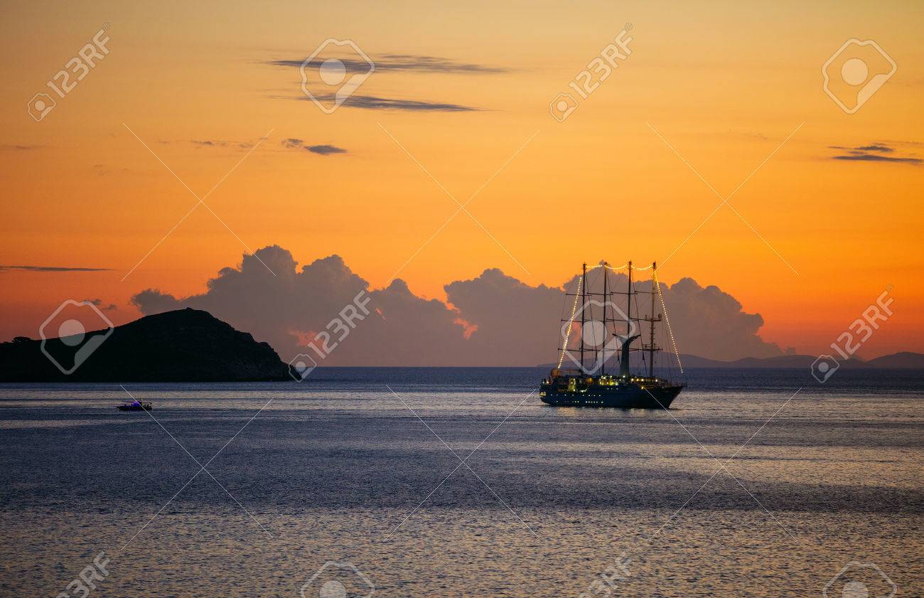View of cruise sailing ship and small ferry boat by rocky coast at sunset - 74710007 View of cruise sailing ship and small ferry boat by rocky coast at sunset - 74710007