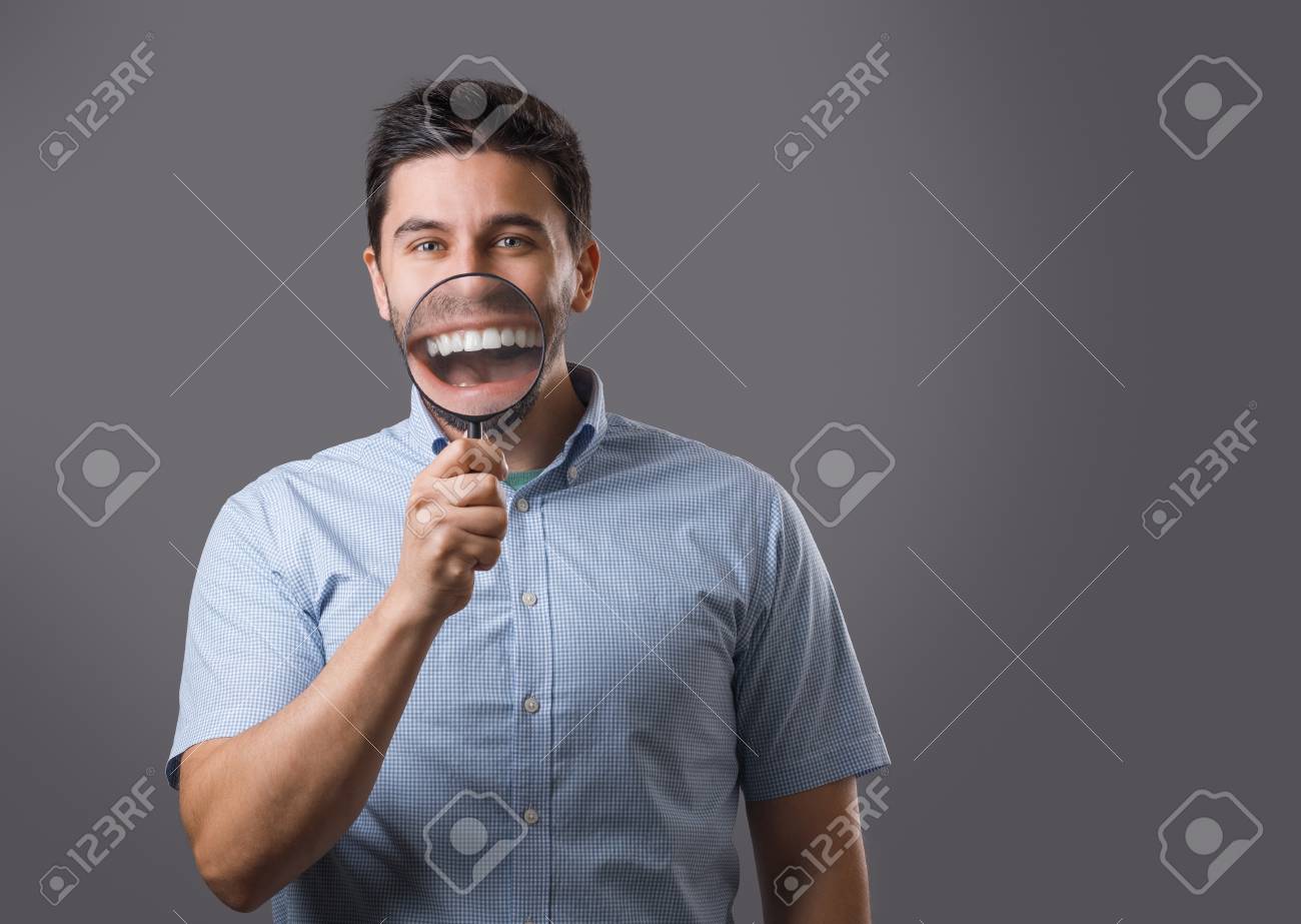 口を大きくする虫眼鏡を持つ若い陽気なひげを生やした男の肖像画 若い男は何かを探して の写真素材 画像素材 Image