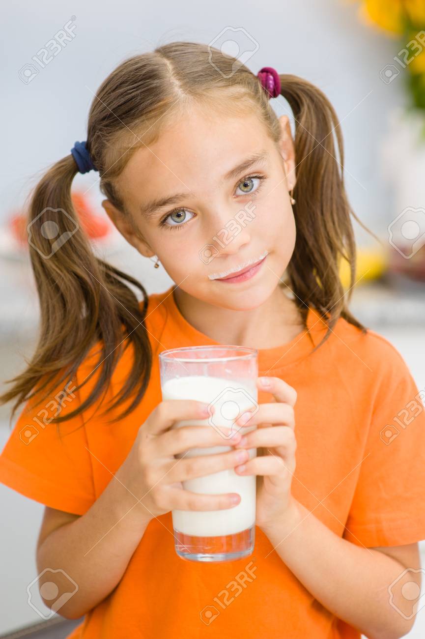 牛乳のガラスを保持しているミルクの口ひげを持つ幸せな小さな女の子 の写真素材 画像素材 Image