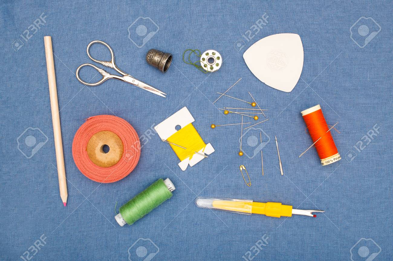 Herramientas Para Coser A Mano Que Incluyen Agujas, Alfileres, Un Dedal Tijeras, Además De Carretes De Hilo De Color Colocados Sobre Una Superficie De Tela Gris Fotos, Retratos, Imágenes Y Fotografía