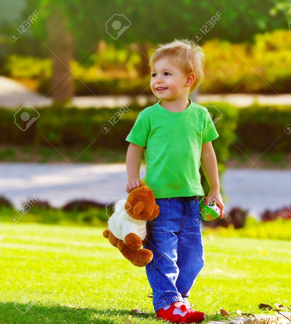 photo of cute small boy in the park holding teddy bear adorable