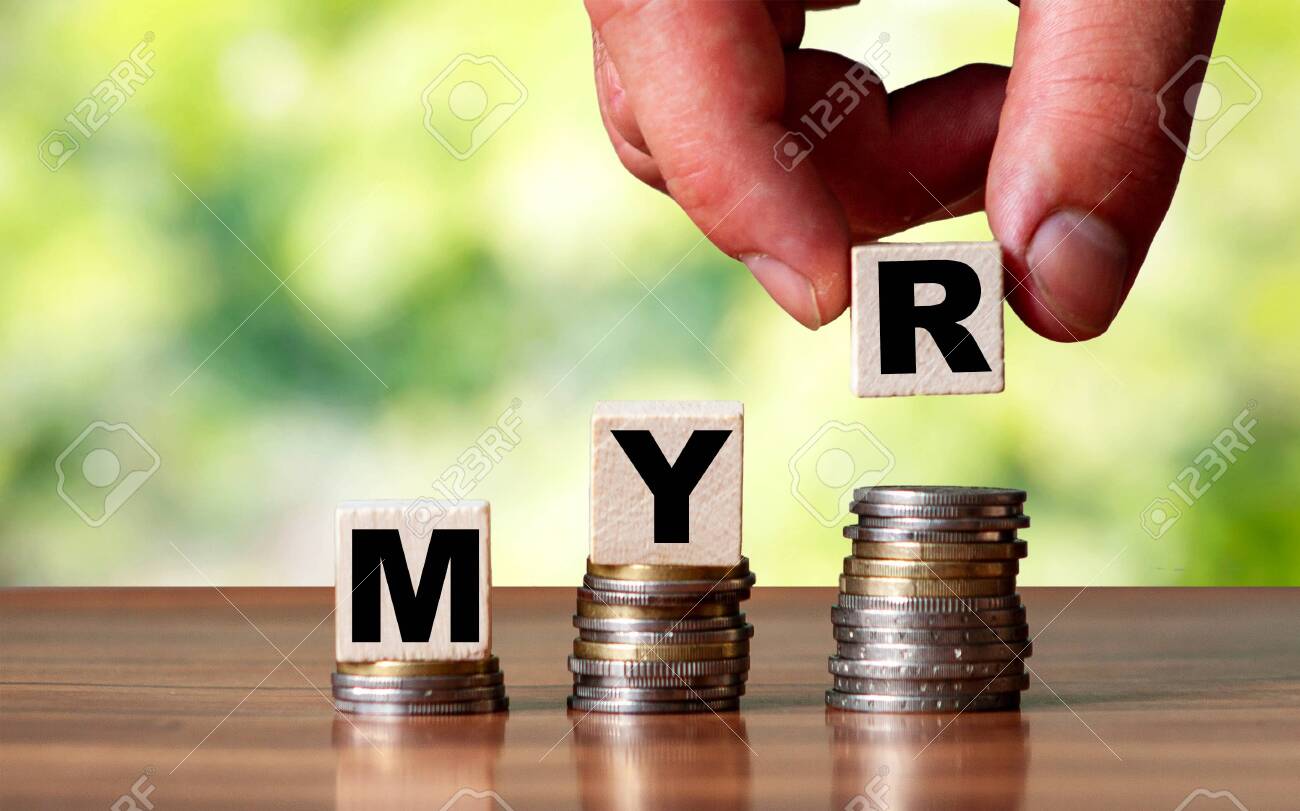 MYRマレーシアリンギット通貨ワードシンボル-ビジネスコンセプト。手は積み重ねられた増加するコインの上に木製のブロックを置きます。の写真素材・画像素材  Image 153438636