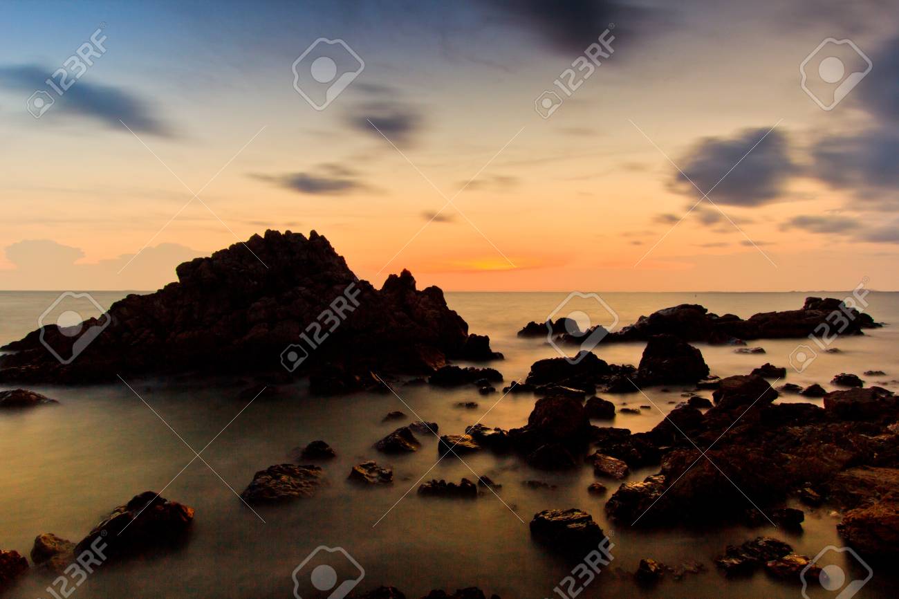 landscape sunset sea waves line impact rock on the beach stock photo