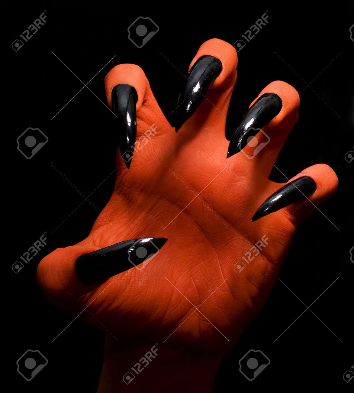 red spooky devil hand on a dark background catching you stock photo