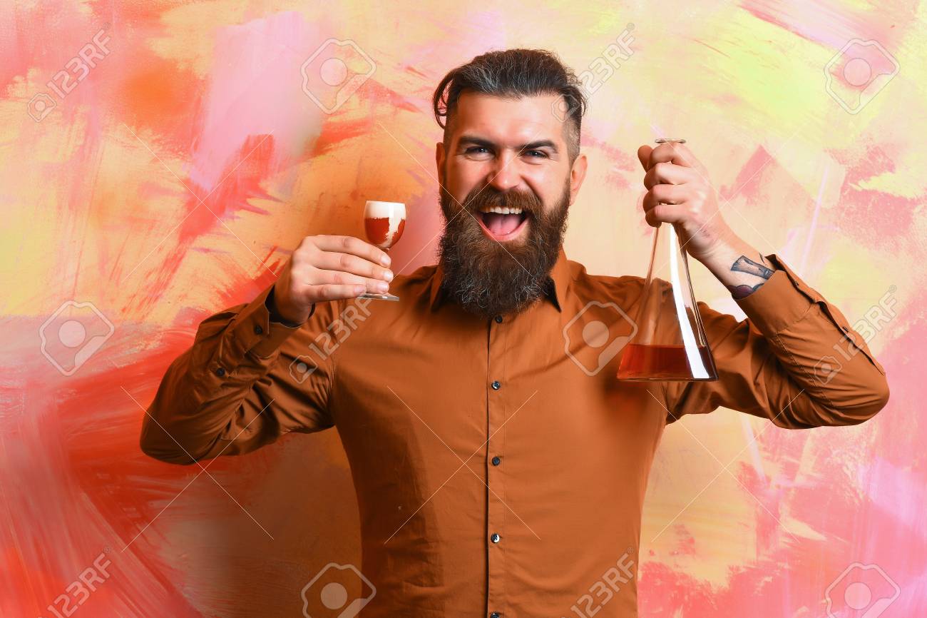 ひげを生やした男は 長いひげ 赤いショットとガラス チューブのアルコールやカラフルなテクスチャ背景にフラスコを保持している茶色のシャツに口ひげを持つ残忍な白人笑顔幸せなヒップスター の写真素材 画像素材 Image