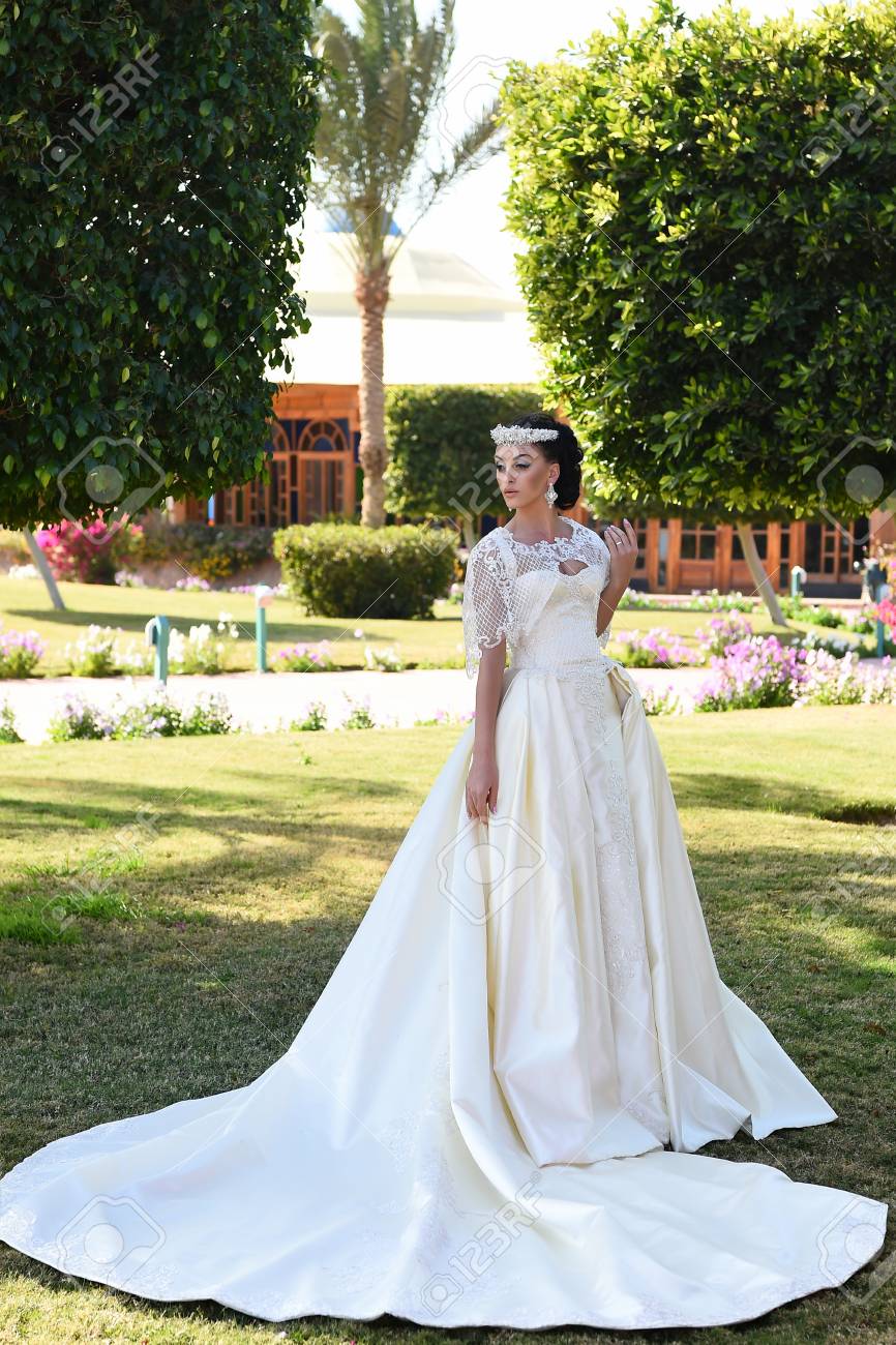 Femme au mariage. jolie femme en robe de mariée de couleur blanche, fille a maquillage à la mode et les cheveux debout en plein air été ensoleillé sur