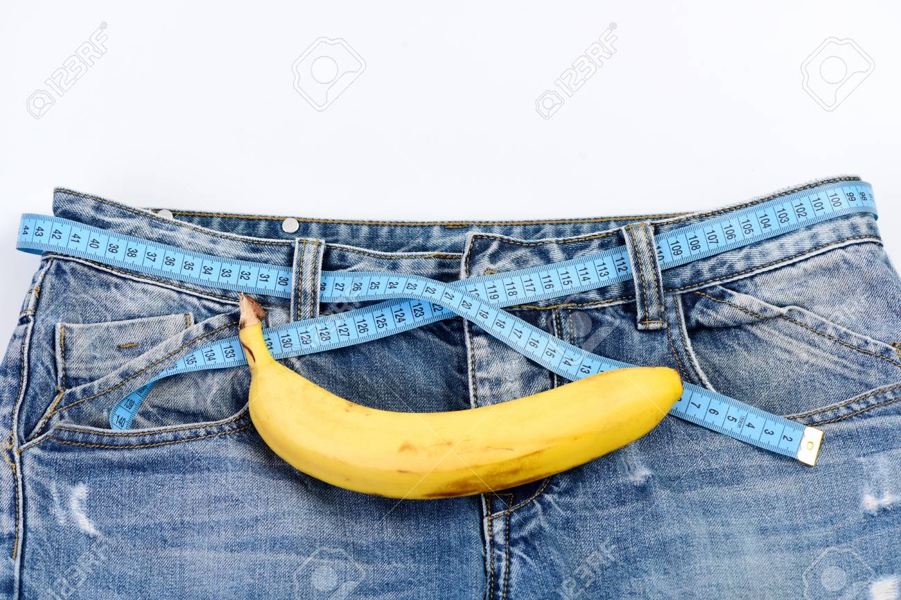 男性性器を模倣してバナナ付きメンズ デニムパンツします デニム生地に変態フルーツをクローズ アップ 健康と男性のセクシュアリティ概念 白い背景の上の ベルトではなくメジャー テープ ブルー ジーンズ の写真素材 画像素材 Image