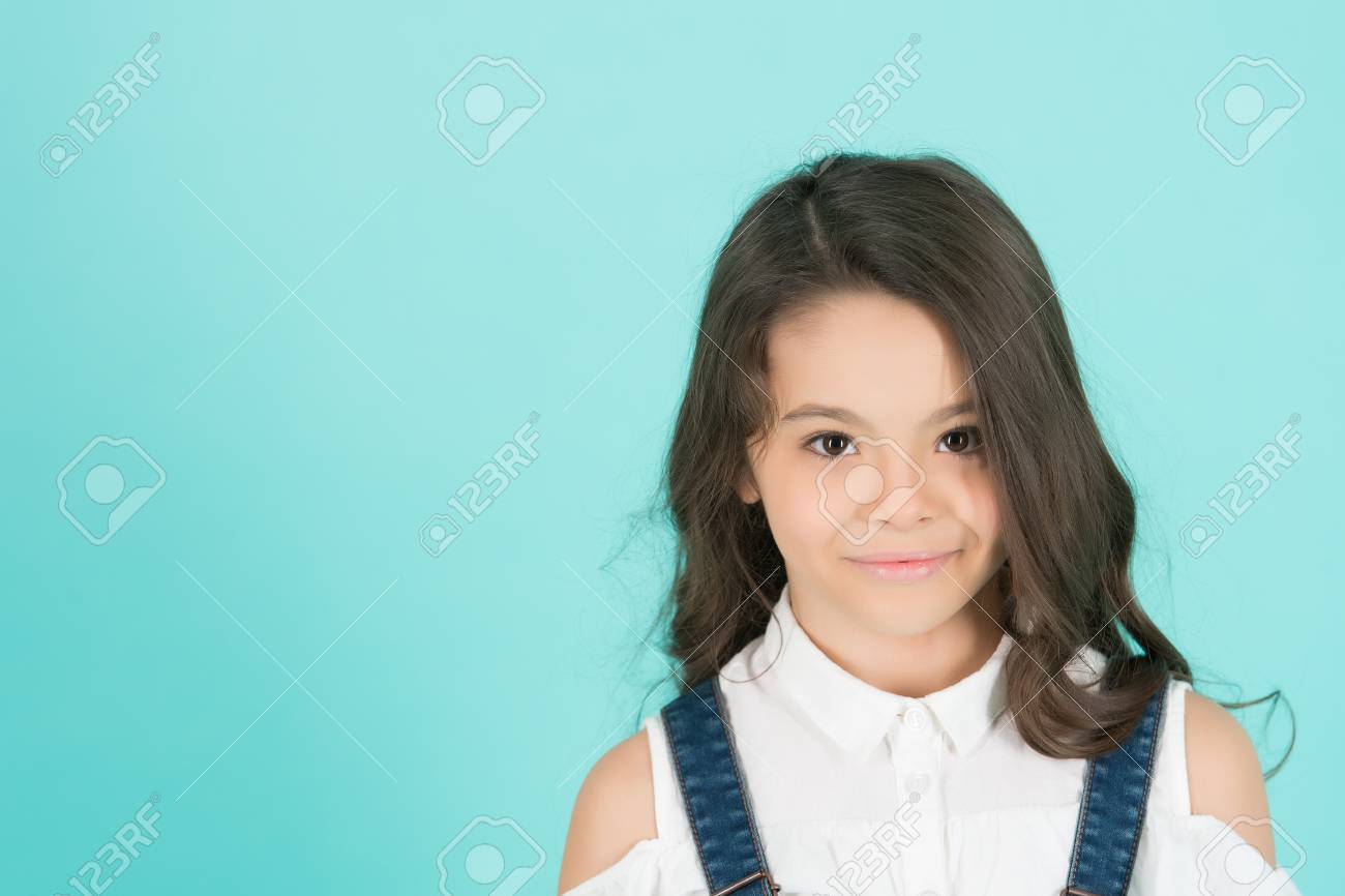 長いブルネットの髪を持つキッドモデル 青い背景にかわいい顔に笑顔の女の子 美しさ 見て 髪型 幸せな子供 子供の頃のコンセプト 青少年 スキンケア 健康 コピースペース の写真素材 画像素材 Image