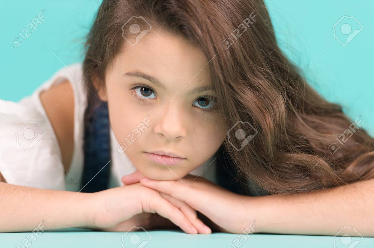 предподростковый Маленькая Девочка С Длинные Волосы Брюнетка Представляют. Маленькая Модель С Очаровательны Кожи Лица На Синем Фоне. Уход За Кожей, Красота, Взгляд, Прическа. Ребенок, Детство, Предподростковый, Юношеский, Пунш Пастель Фотография, картинки, изображения и