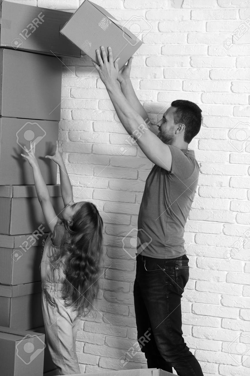 Daughter Puts Hands Up And Father Puts Boxes In Pile Stock Photo